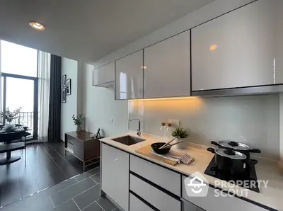 Modern kitchen with sleek cabinetry and dining area in open layout apartment