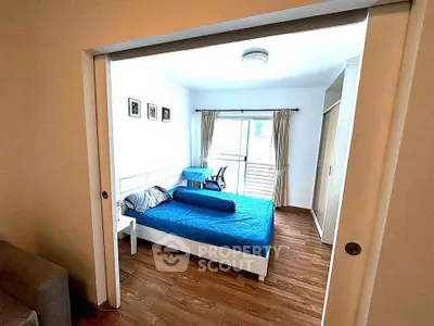 Spacious bedroom with wooden flooring and large window for natural light