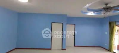 Spacious living room with blue walls and ceiling fan, ideal for modern decor.