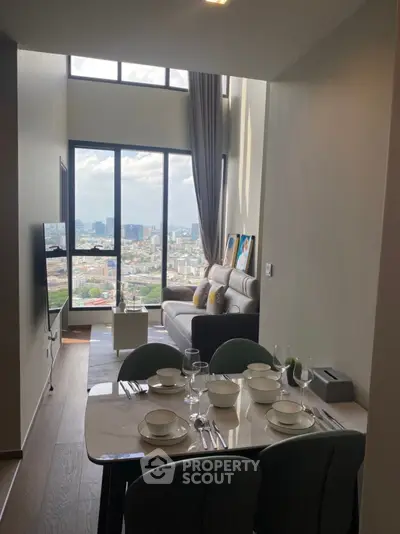 Modern living room with high ceiling and city view, featuring elegant dining setup.
