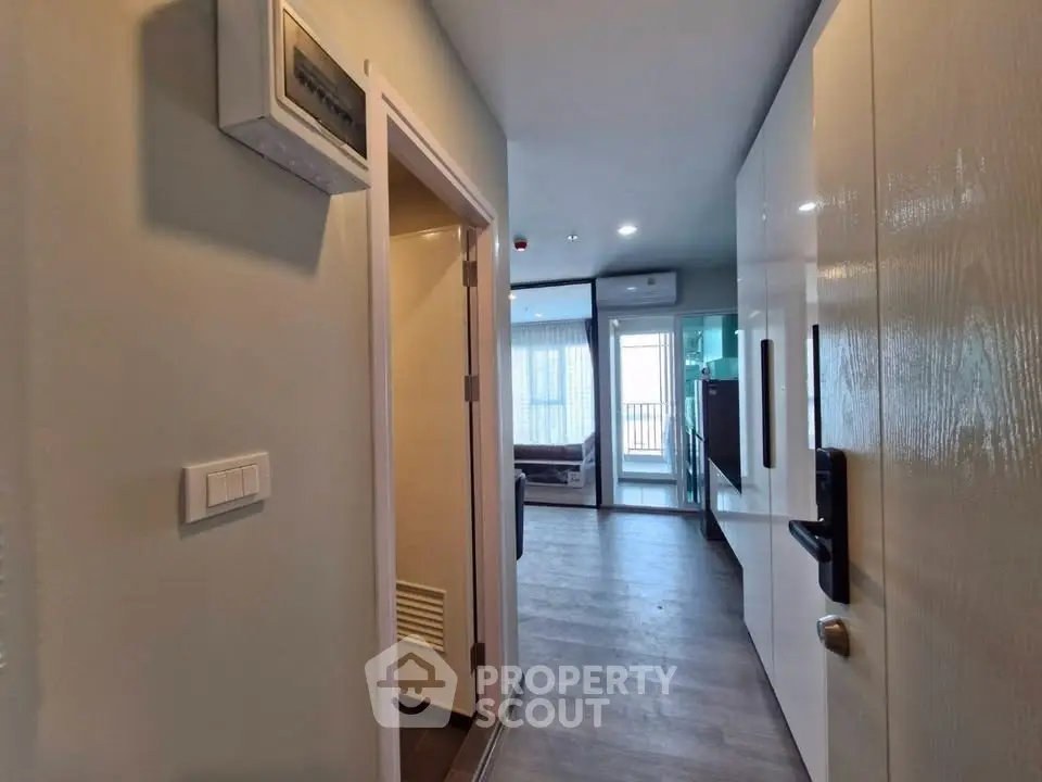 Modern apartment hallway with sleek design and wooden flooring leading to a bright living area.