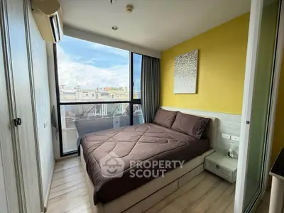 Modern bedroom with large window and city view, featuring stylish decor and cozy atmosphere.