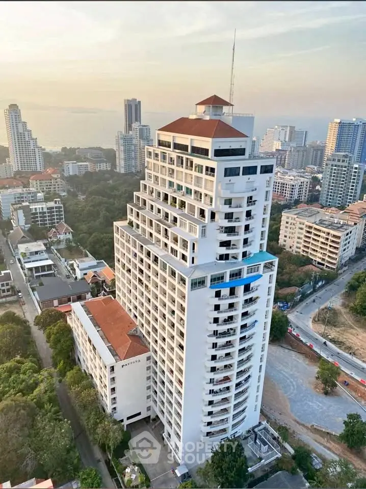 Stunning aerial view of a modern high-rise building with panoramic cityscape and ocean backdrop.