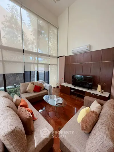 Spacious living room with modern decor, large windows, and cozy seating area.