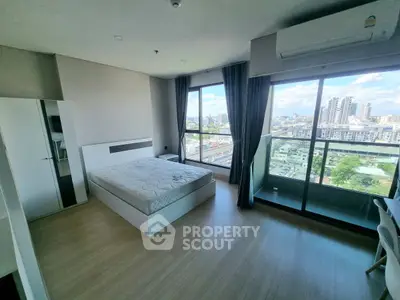 Spacious bedroom with city view and balcony access in modern apartment