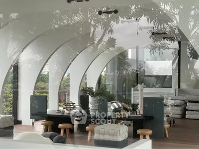 Luxurious modern living room with arched windows and stylish decor, offering a serene view of lush greenery.