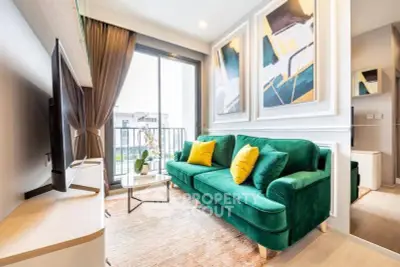 Stylish living room with green velvet sofa and modern art, featuring a cozy balcony view.