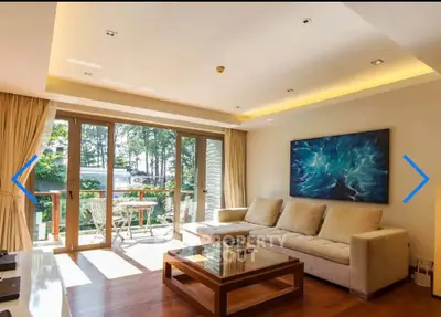 Spacious living room with large windows and balcony access, featuring modern decor and natural light.