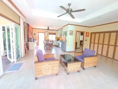 Spacious open-plan living room with stylish wicker furniture and ceiling fan, perfect for modern living.