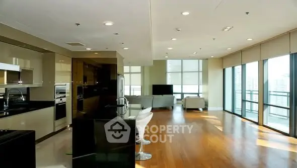 Spacious modern living room with open kitchen and large windows offering city views.