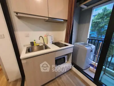 Compact kitchen with modern appliances and balcony view in urban apartment