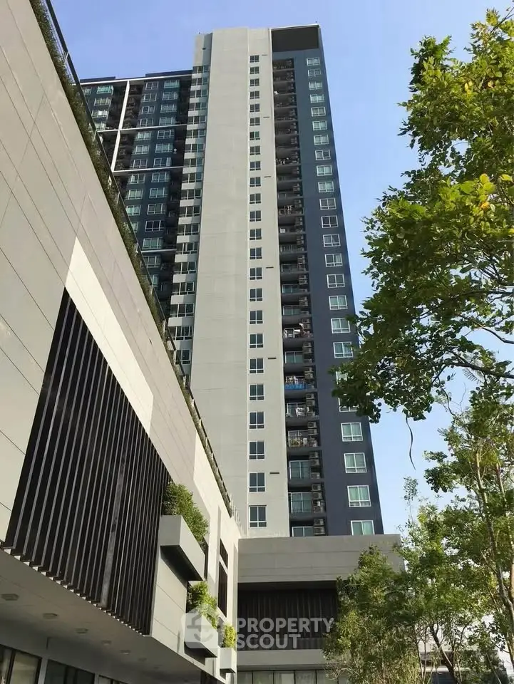 Modern high-rise building with sleek design and lush greenery, perfect for urban living.