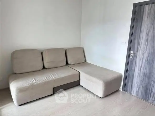 Modern living room with stylish beige sectional sofa and sleek wooden door.