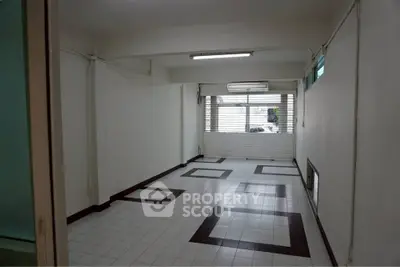 Spacious empty room with tiled floor and large window, ideal for customization.
