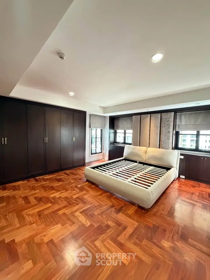 Spacious bedroom with elegant wooden flooring and ample natural light.