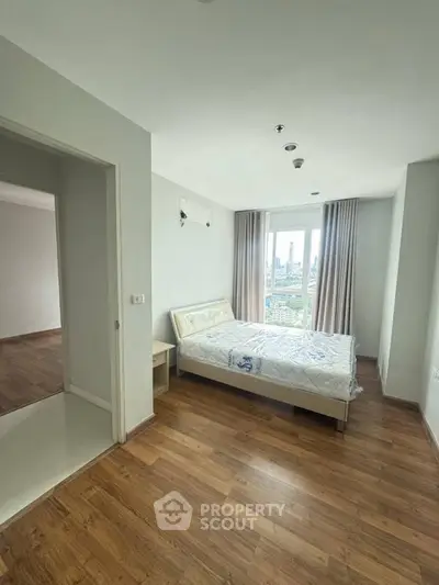 Spacious bedroom with city view and wooden flooring in modern apartment