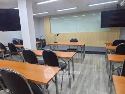 Modern conference room with sleek tables, chairs, and presentation screens, ideal for meetings and seminars.