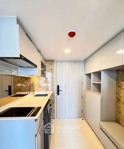 Modern compact kitchen with sleek cabinetry and built-in appliances in a stylish apartment.