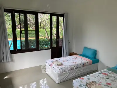 Bright bedroom with pool view, featuring twin beds and large windows for natural light.