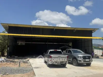 Spacious industrial warehouse with ample parking and modern design under a clear blue sky.