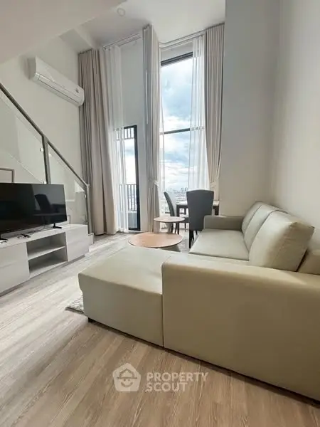 Modern living room with high ceilings and large windows offering stunning views.
