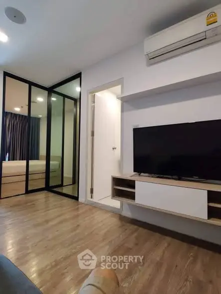 Modern living room with sleek design and glass partition leading to bedroom