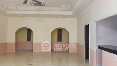 Spacious living room with elegant arches and ceiling fan, perfect for modern living.