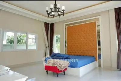Luxurious bedroom with elegant chandelier and tufted headboard, featuring large windows and stylish decor.