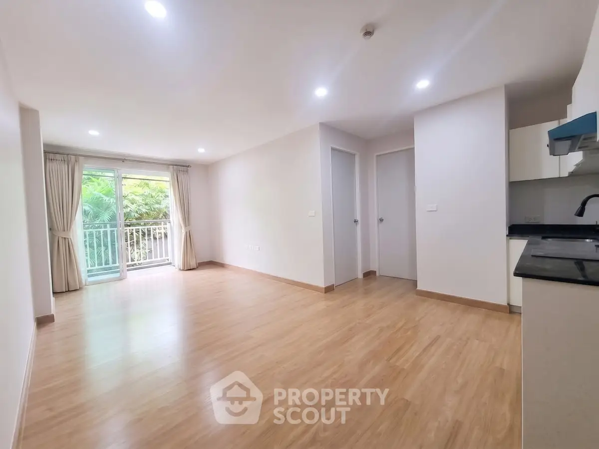 Spacious living room with wooden flooring and balcony view in modern apartment