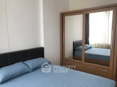 Modern bedroom with sleek mirrored wardrobe and cozy blue bedding.