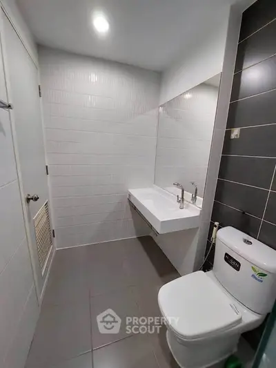 Modern bathroom with sleek fixtures and minimalist design, featuring a wall-mounted sink and contemporary tiles.
