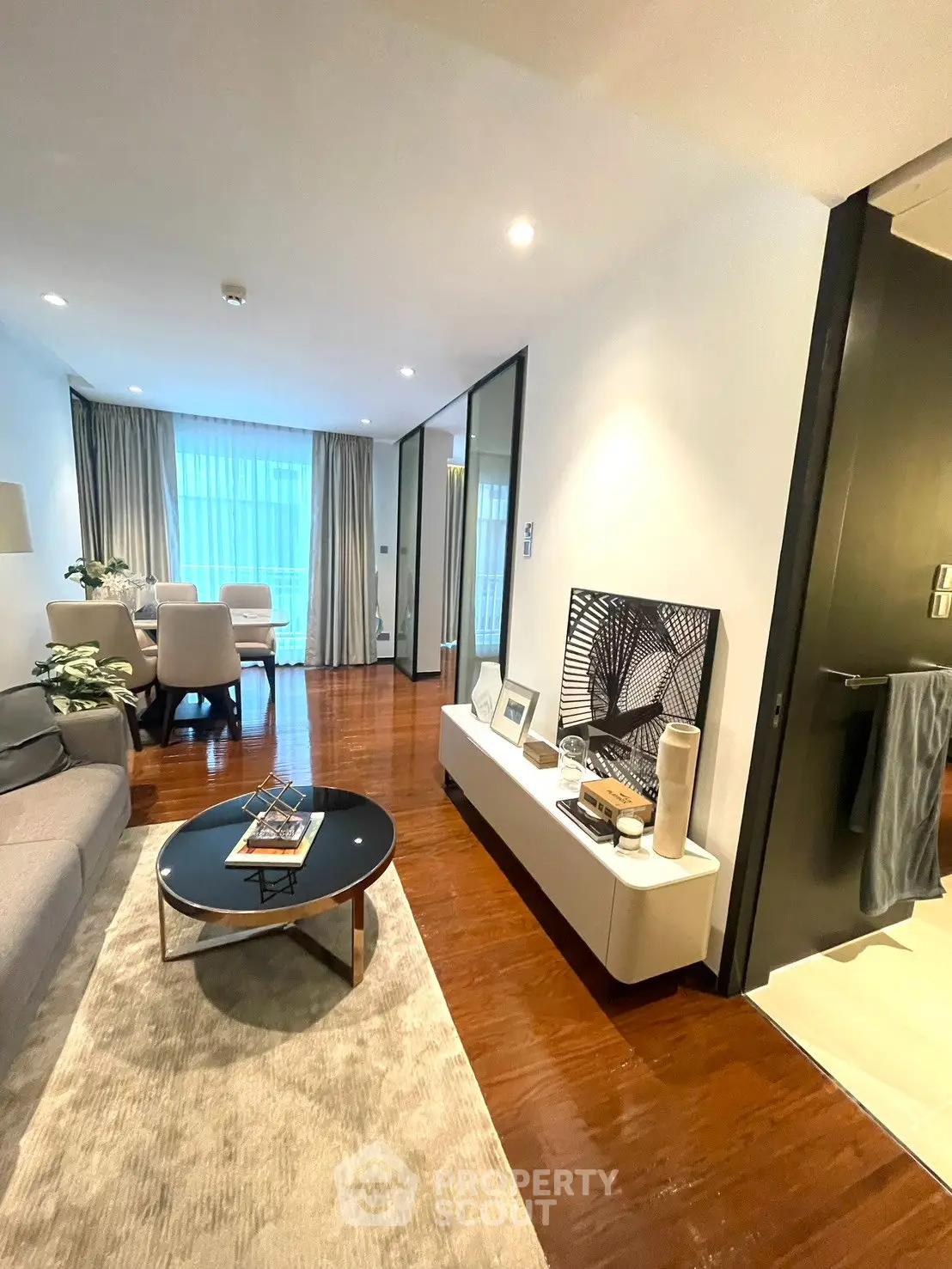 Modern living room with elegant decor and wooden flooring, featuring a cozy seating area and stylish dining space.