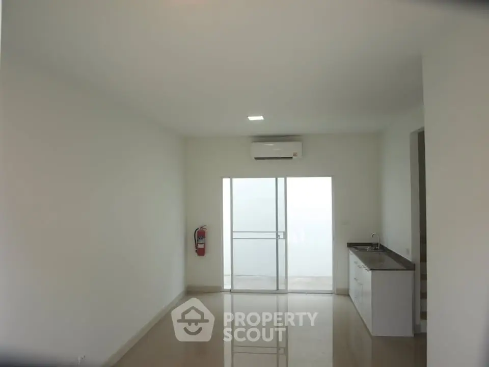 Spacious modern living room with sleek flooring and large window for natural light.
