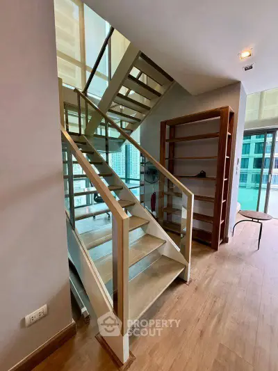 Modern duplex apartment with stylish wooden staircase and open living area, featuring floor-to-ceiling windows.