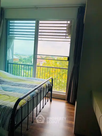 Cozy bedroom with large window offering scenic view and natural light.