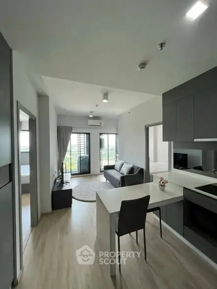 Modern open-plan living room with sleek kitchen and balcony view, perfect for urban living.