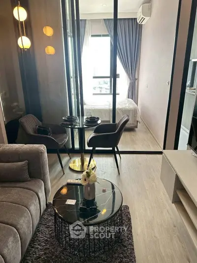 Modern living room with cozy seating and stylish decor leading to a bright bedroom.