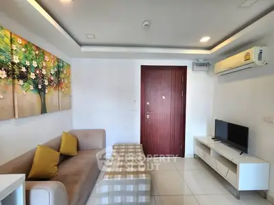 Modern living room with stylish decor and air conditioning, featuring a cozy sofa and flat-screen TV.