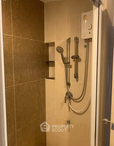 Compact bathroom shower area with modern fixtures and neutral tiles.