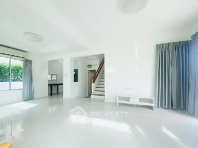 Spacious and bright living room with modern staircase and large windows