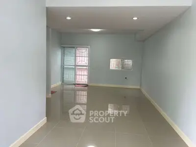 Spacious empty room with glossy tiled floors and large window for natural light.