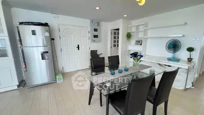 Modern dining area with glass table and sleek black chairs in a bright apartment.