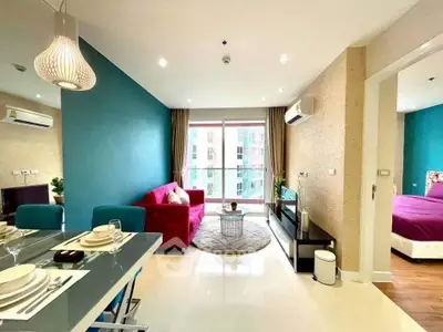 Modern open-plan living room with vibrant decor and natural light in a stylish apartment.