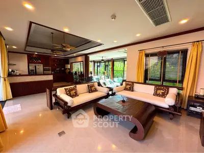 Spacious living room with elegant wooden furniture and open kitchen layout, perfect for modern living.