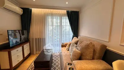 Cozy living room with plush sofa, TV, and elegant curtains