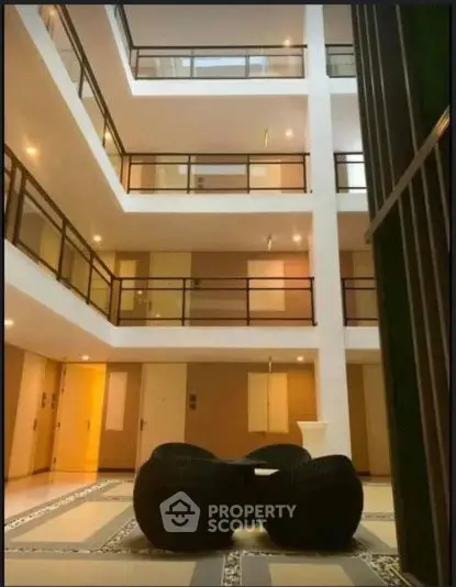 Modern multi-story building interior with stylish seating area and bright lighting.