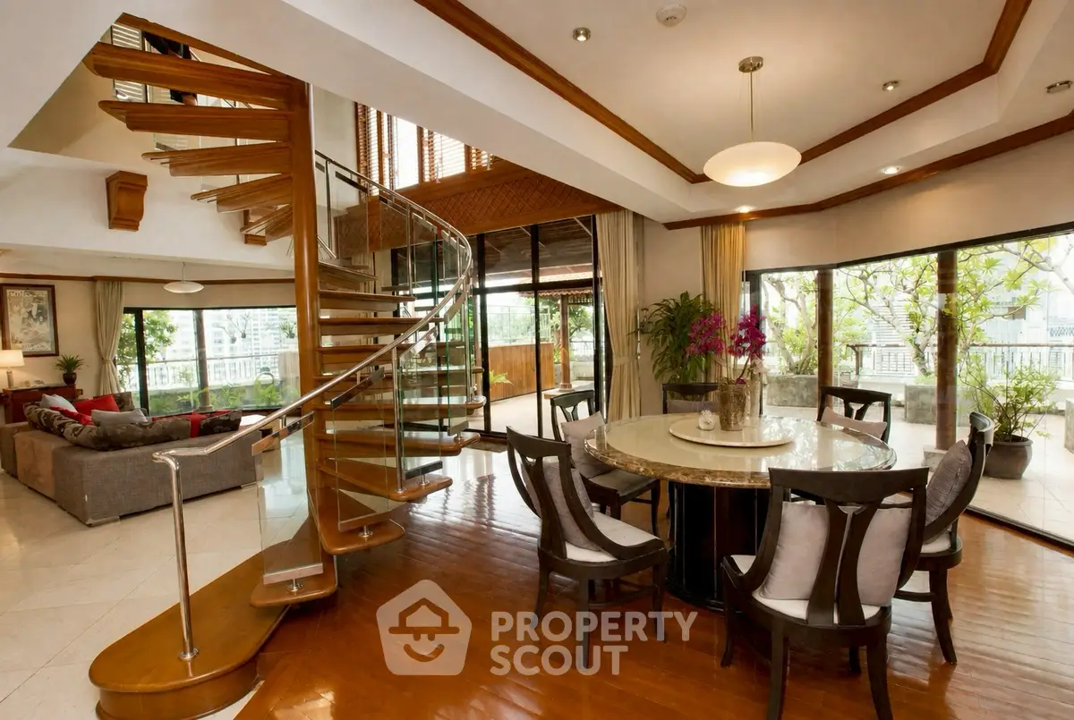 Luxurious open-plan living room with spiral staircase and large windows offering stunning views.