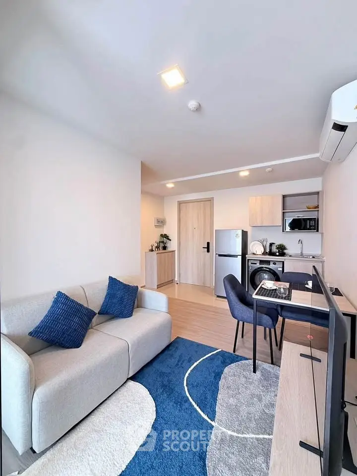 Modern living room with open kitchen, stylish decor, and cozy seating area in a contemporary apartment.