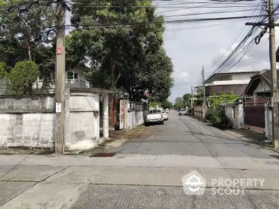 Charming residential street view with lush greenery and parked cars, ideal for serene living.