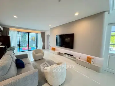 Modern living room with sleek design and pool view, featuring stylish furniture and large TV.